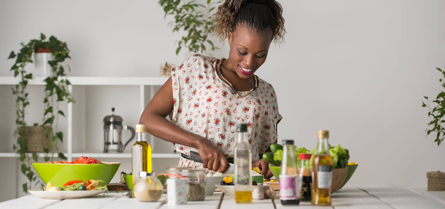 Young African Woman Cooking. Healthy Food - Vegetable Salad.